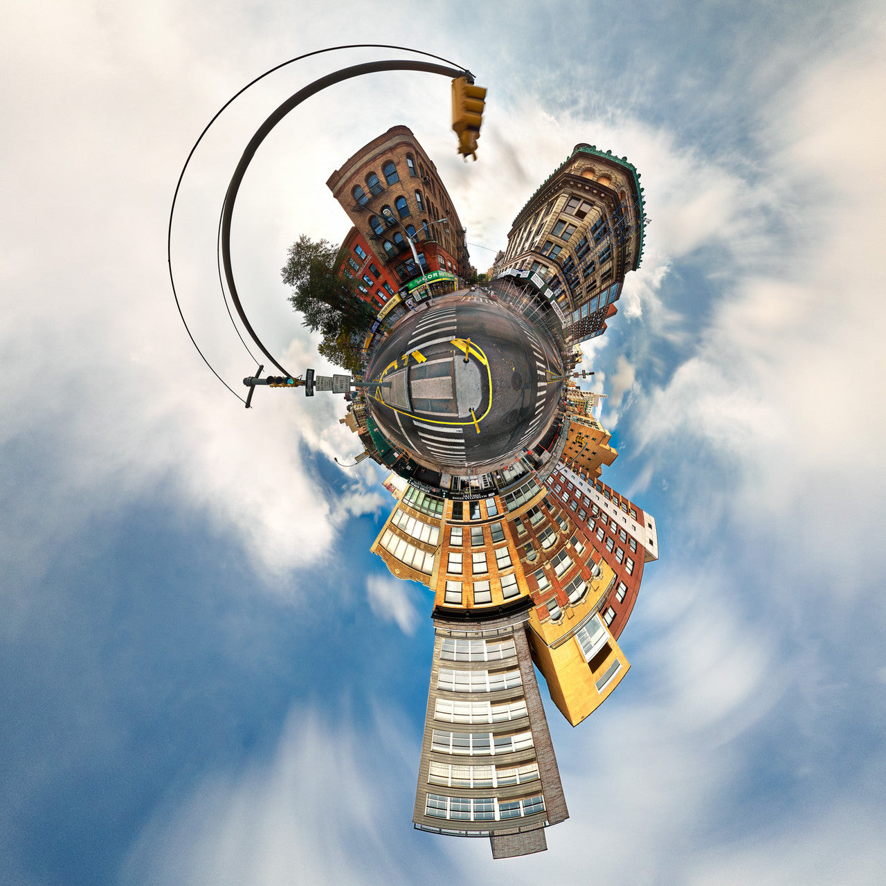 A 360-degree panoramic Spherescape of the intersection of Spring St and Bowery St in the Lower East Side of NYC, with buildings warping around the edges and streets converging in the center, under a cloudy sky.