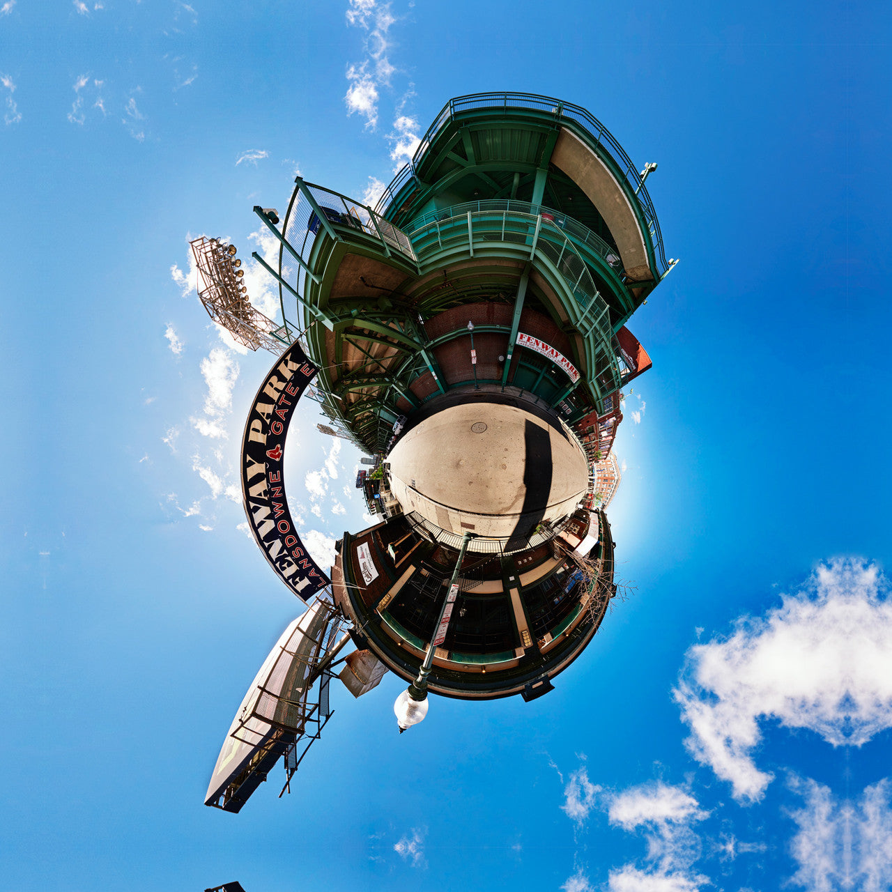 A 360-degree panoramic image of Fenway Park's Lansdowne Gate in Boston, displaying the iconic red and green stadium exterior and sign, enveloped in a spherical perspective with a vivid blue sky.