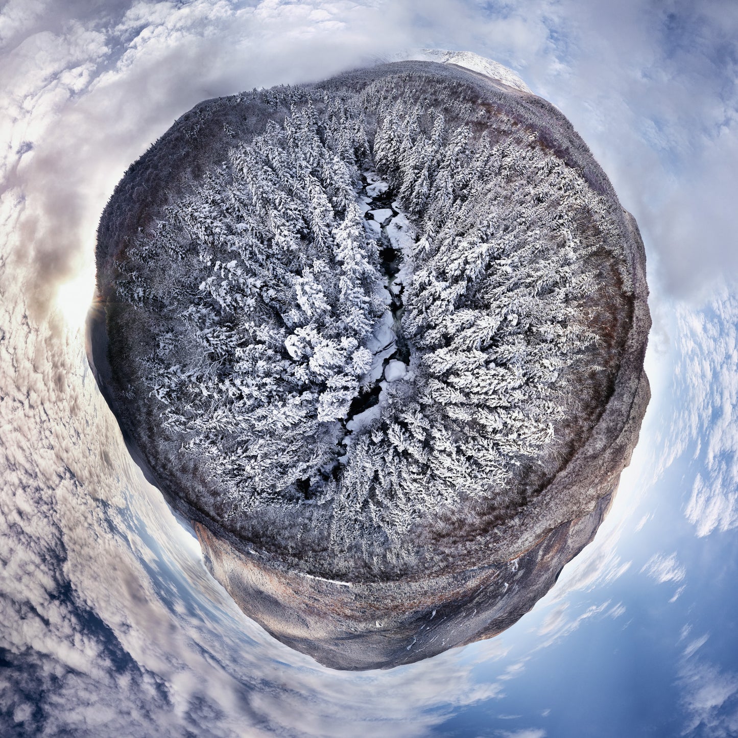 Spherical panoramic photograph of Crystal Cascade in winter, showing a snow-covered stream cutting through frost-covered evergreens, creating a perfect circular landscape against a clouded mountain sky.