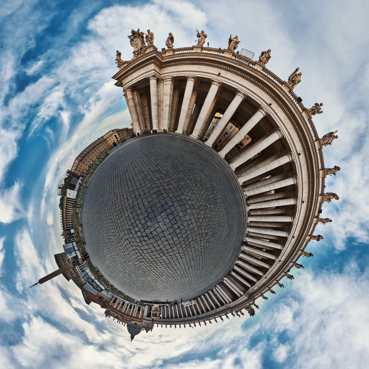 Spherical panoramic photograph of St. Peter's Square, showing Bernini's colonnade radiating in a perfect circle, crowned with saint statues and centered on geometric cobblestone patterns, set against a dramatic blue and clouded sky.