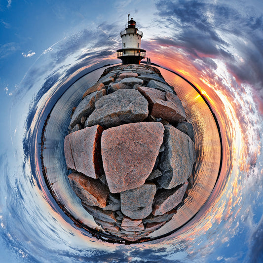 A 360-degree panoramic photograph of Spring Point Ledge lighthouse at sunrise, showing a circular view of the granite pier, lighthouse, and vibrant sky reflected in the surrounding water.