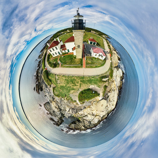 360-degree “tiny planet” image of Beavertale Light in Rhode Island, with the lighthouse, red-roofed buildings, grassy headland, rocky cliffs, and surrounding blue ocean wrapped into a small circular world under a bright, cloud-streaked sky.