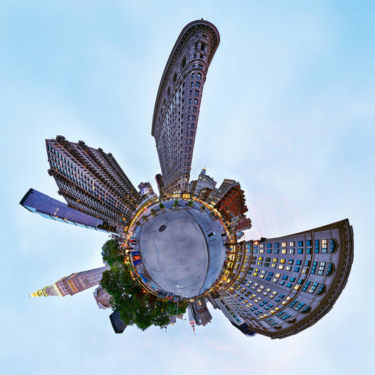 A 360-degree panoramic spherescape of the Flatiron Building and Madison Square Park during the blue hour, with the surrounding architecture wrapping around a central point under a twilight sky.