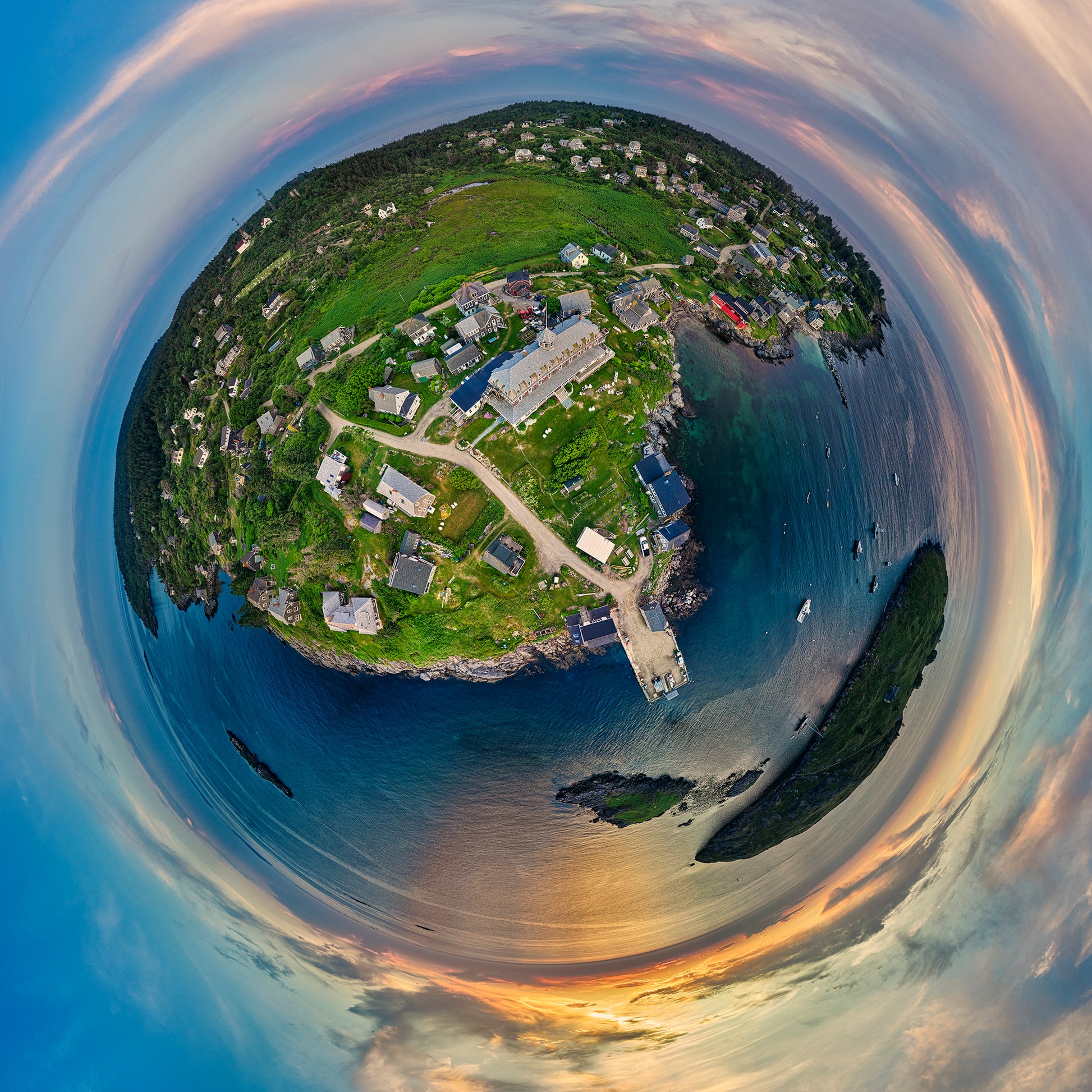 Spherical panoramic photograph of Monhegan Island at sunset, showing the Island Inn, scattered cottages, and rocky coastline surrounded by ocean, with golden sunset clouds creating a circular horizon.