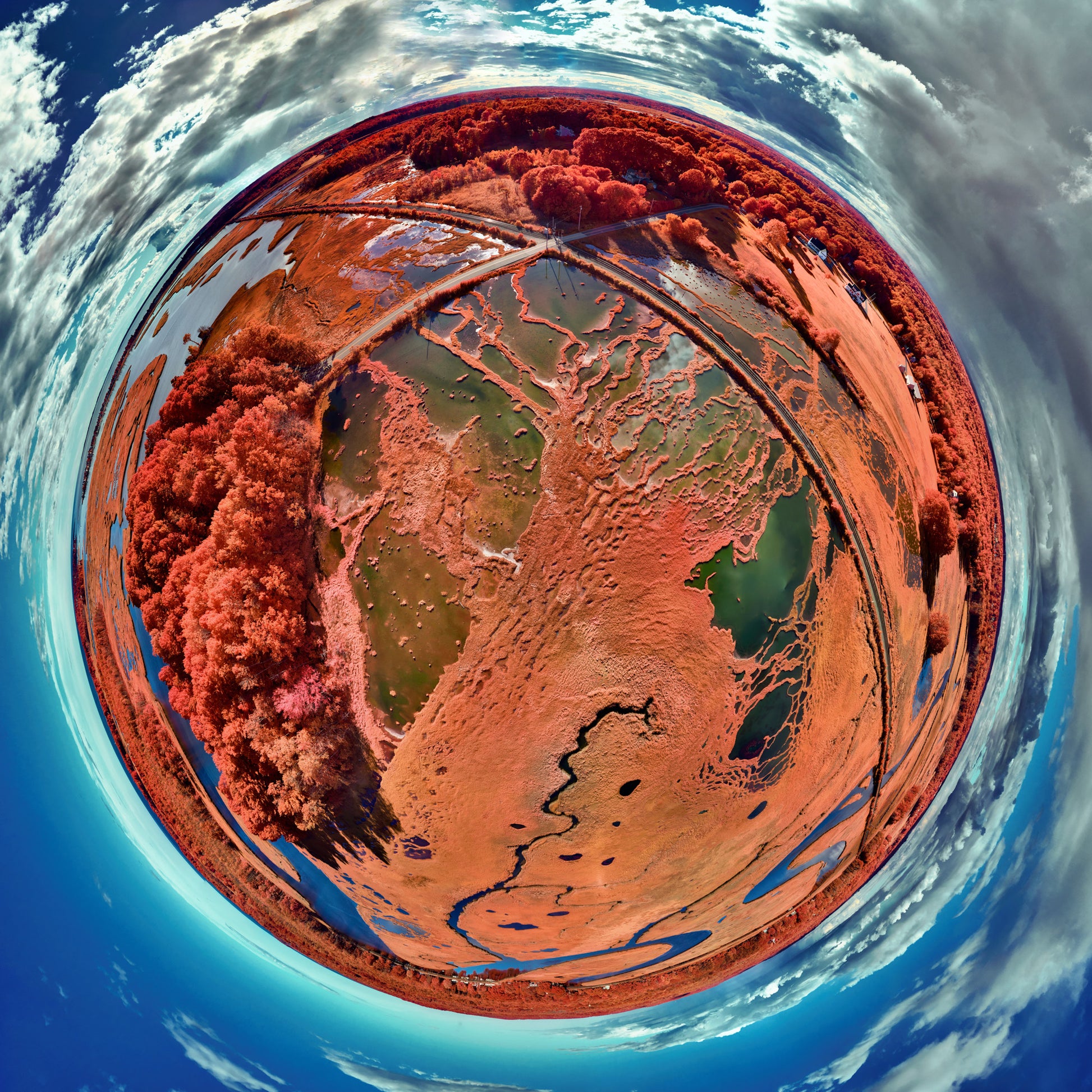 Spherical panoramic infrared photograph of the Nonesuch River, showing meandering waterways through crimson-colored salt marshes, creating a perfect circular landscape against a turquoise sky.