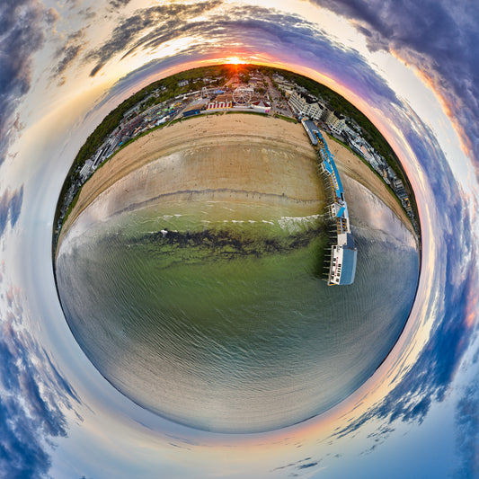 Alt text:
360-degree “tiny planet” image of Old Orchard Beach Pier at sunset, with a glowing sandy beach, amusement park, pier buildings over green water, and dramatic violet-orange clouds wrapped into a circular world.