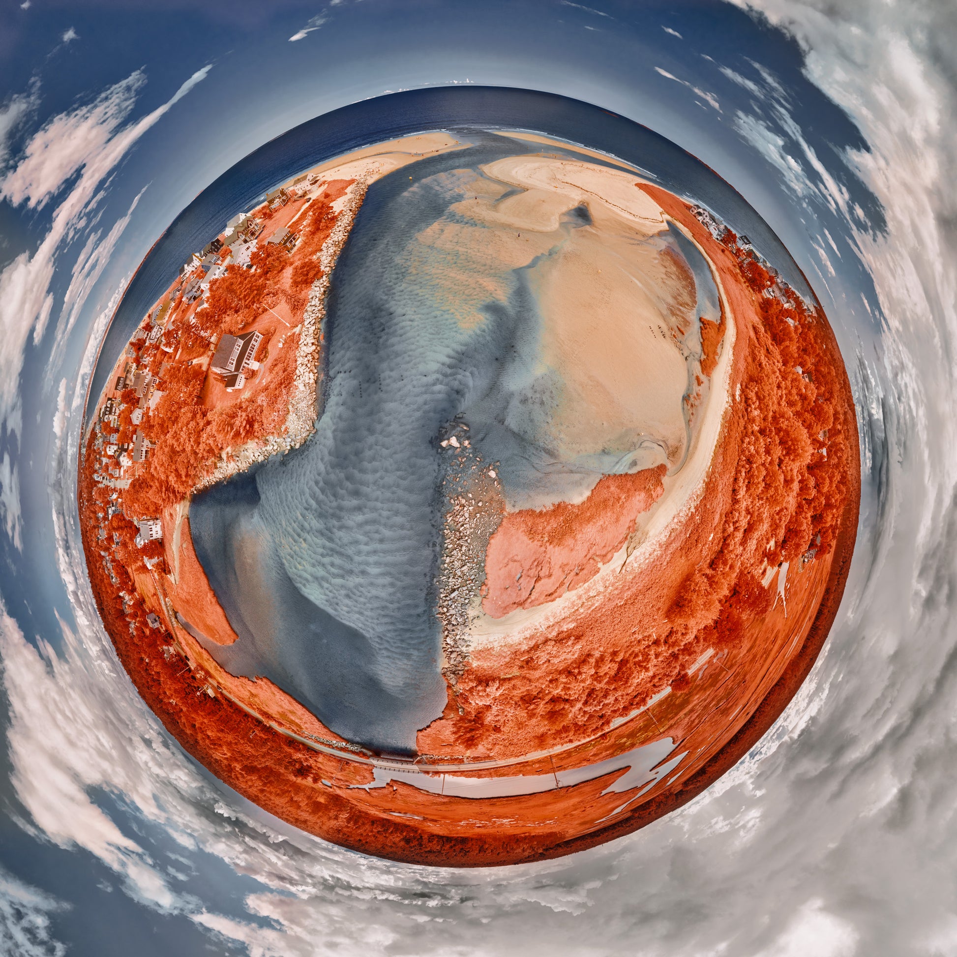 A 360-degree infrared panoramic photograph of Ocean Park, Maine, featuring crimson vegetation, silver-blue water channels, and swirling clouds, creating a surreal, Martian-like landscape.