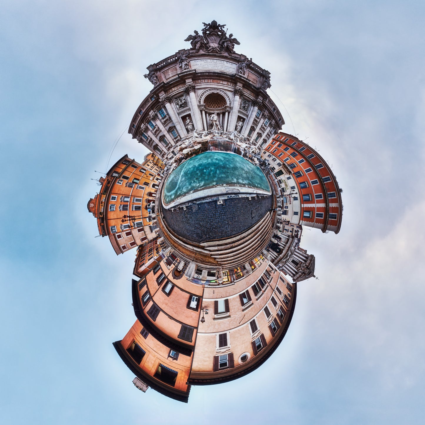 Spherical panoramic photograph of the Trevi Fountain in Rome, showing its ornate baroque facade rising above a swirling pattern of traditional orange-hued buildings and turquoise water, creating a spiraling effect against a light blue sky.